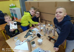 Czterech chłopców przy stoliku, w trakcie składania robota.