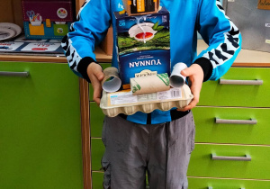 Uczeń na tle szafek prezentuje robota.
