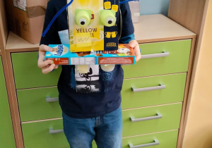 Uczeń na tle szafek prezentuje kolorowego robota.