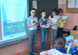 Troje uczniów przed tablicą multimedialną