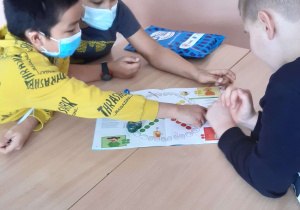 Trzech uczniów pracuje przy stoliku