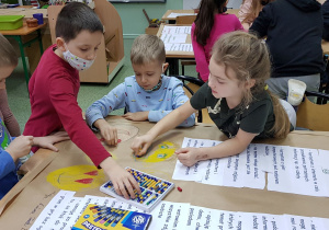 Uczniowie pracują przy ławkach- tworzą kartę pracy grupy