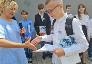 Dyrekcja szkoły wręcza uczniowi nagrodę książkową