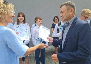 Dyrekcja szkoły wręcza ojcu list gratulacyjny