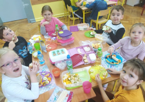 Grupa uczniów spożywa śniadanie przy wspólnym stole