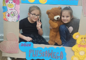 Dwie uczennice w fotobudce z misiem