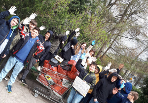 Uczniowie z koszem pełnym worków ze śmieciami