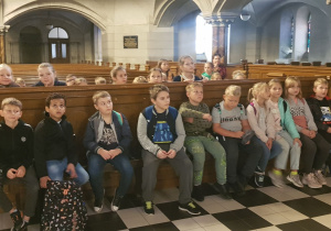 Uczniowie klas trzecich w ławkach nawy głównej kościoła