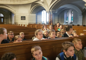Uczniowie klas trzecich w ławkach nawy głównej kościoła