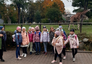 Grupa dzieci na tle wybiegu dla żyrafy