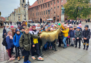 Dzieci głaszczą pręgierz- metalowego osła.