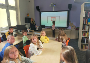 Grupa uczniów w trakcie zajęć w pomieszczeniu biblioteki