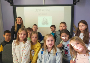 Grupa uczniów z prowadzącą zajęcia przed tablicą ze slajdem o słynnych łodzianach