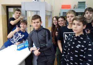 Grupa uczniów przy stole roboczym w pracowni chemicznej