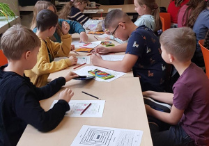 Uczniowie rozwiązują zadania na kartkach