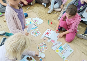 Uczennice naklejają rysunki na szary papier