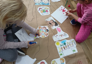 Uczennice porządkują rysunki na szary papier