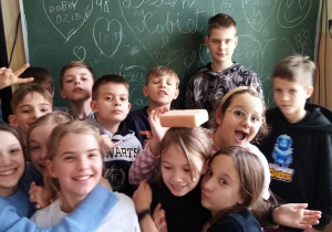 Grupa uczniów na tle tablicy z wpisami- życzeniami