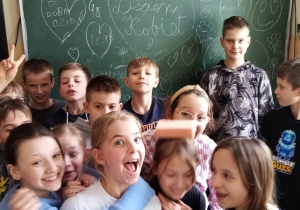 Grupa uczniów klasy 4 na tle tablicy z wpisami okolicznościowymi