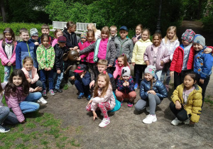 Uczniowie stoją przy pomniku Plastusia w Parku Sienkiewicza.