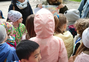 Przewodniczka pokazuje dzieciom pieczątkę z bajki Maurycy i Hawranek