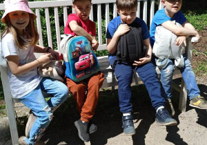 Czworo uczniów siedzi na ławce w parku.