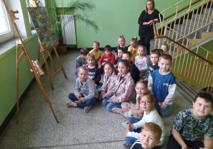 Uczniowie klasy 1a przed sztalugami ze zdjęciami nauczycieli