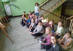 Uczniowie klasy 2b przed sztalugami ze zdjęciami nauczycieli