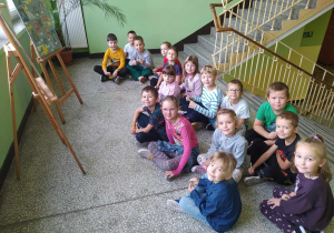Uczniowie klasy 1b przed sztalugami ze zdjęciami nauczycieli