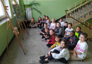 Uczniowie klasy 3a przed sztalugami ze zdjęciami nauczycieli