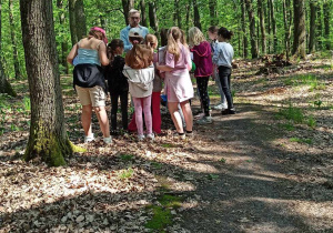 Uczniowie klasy IIb z edukatorem w środku lasu