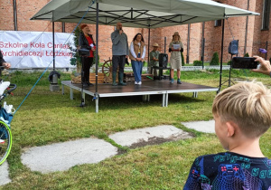 Rozpoczęcie pikniku. Na scenie prowadzący, a w tle kościół Przenajświętszej Trójcy