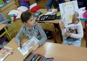 Dzieci kolorują obrazki z misiem.