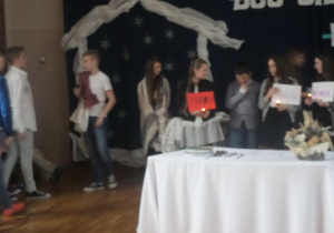 Scena z jasełek, na środku stół, a za nim uczniowie- aktorzy.