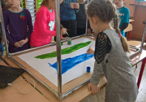 Uczniowie malują farbami.