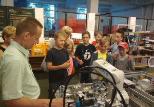 Uczniowie obserwują pracę robotów przemysłowych linii produkcyjnej.