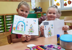 Dziewczynki prezentują w zeszytach piramidy zdrowego żywienia.