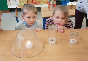 Dzieci obserwują gasnącą świecę.