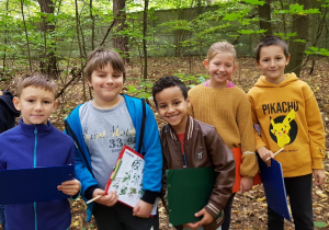 Sześcioro uczniów z kartami pracy w lesie