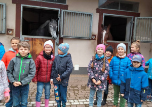 Grupa dzieci, konie w boksach