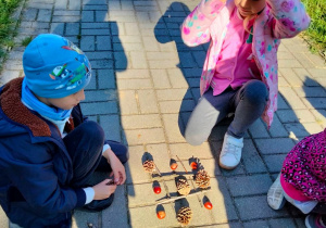 Uczniowie grają w kółko i krzyżyk szyszkami i kasztanami
