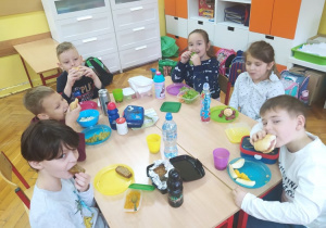 Grupa uczniów spożywa śniadanie przy wspólnym stole