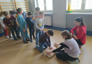 Grupa dzieci uczy się resuscytacji oddechowo-krążeniowej.