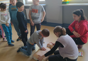 Grupa dzieci uczy się resuscytacji oddechowo-krążeniowej.