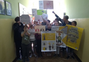 Uczniowie z plakatami na korytarzu szkolnym