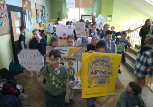 Duża grupa uczniów z plakatami na korytarzu szkolnym