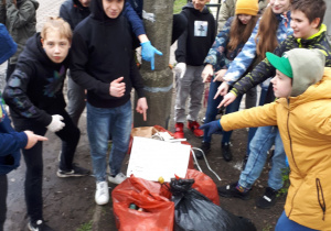 Grupa uczniów podczas zbiórki śmieci wokół szkoły