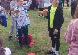 Dzieci jedzą hot dogi.