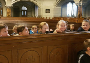 Uczniowie klas trzecich w ławkach nawy głównej kościoła