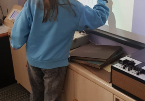 Dziewczynka uzupełnia krzyżówkę na tablicy multimedialnej.